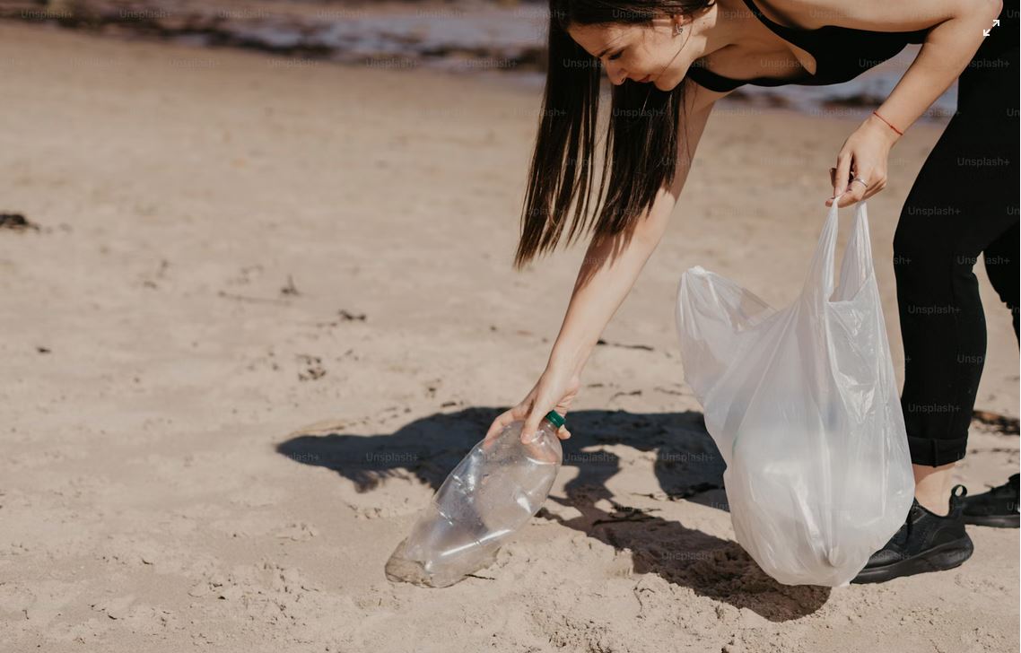 Eine Frau hebt Müll auf